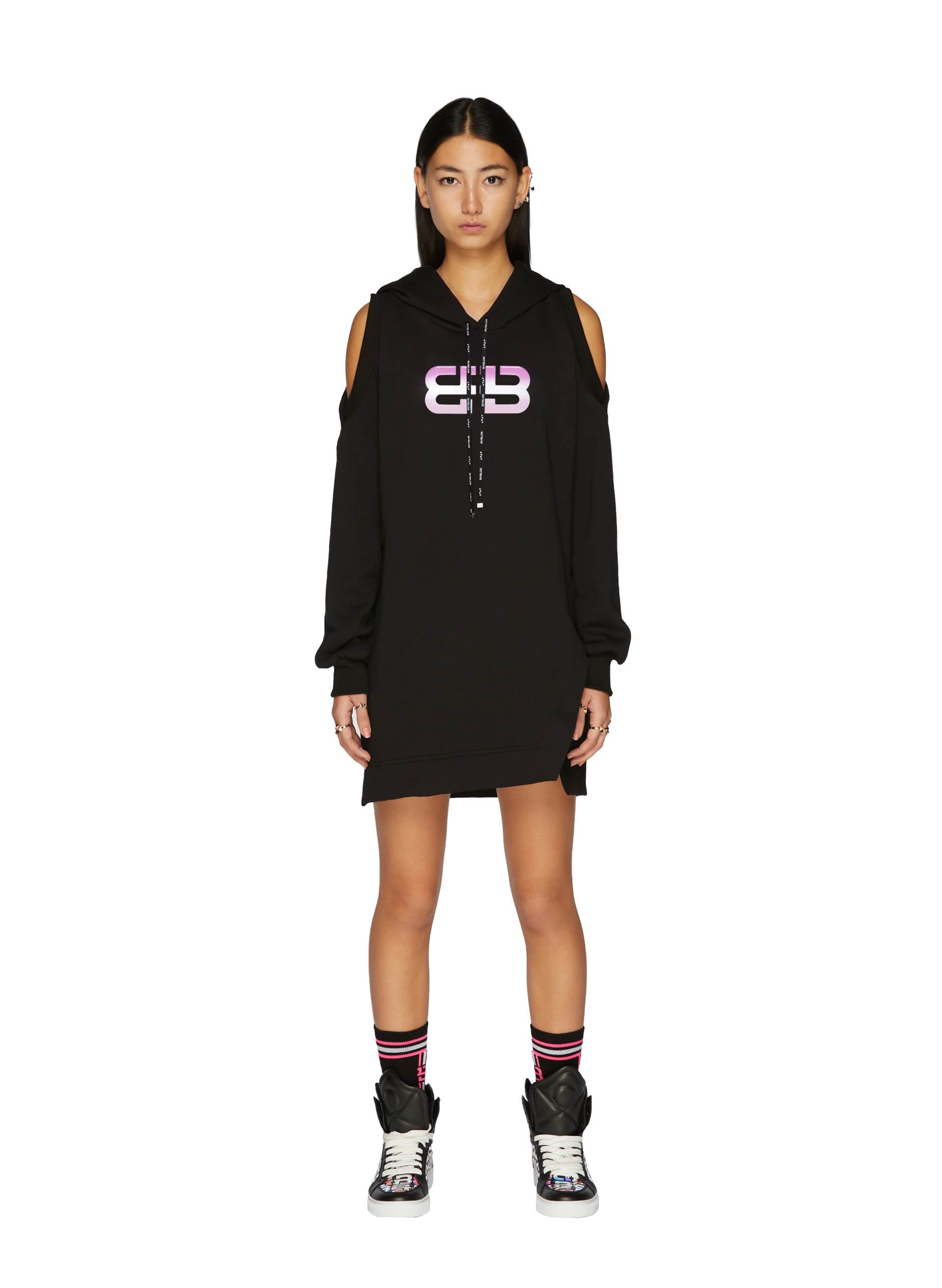 Black Monogram Cotton Dress with cut-out sleeves and vibrant logo, styled with sporty high-top sneakers and striped socks.