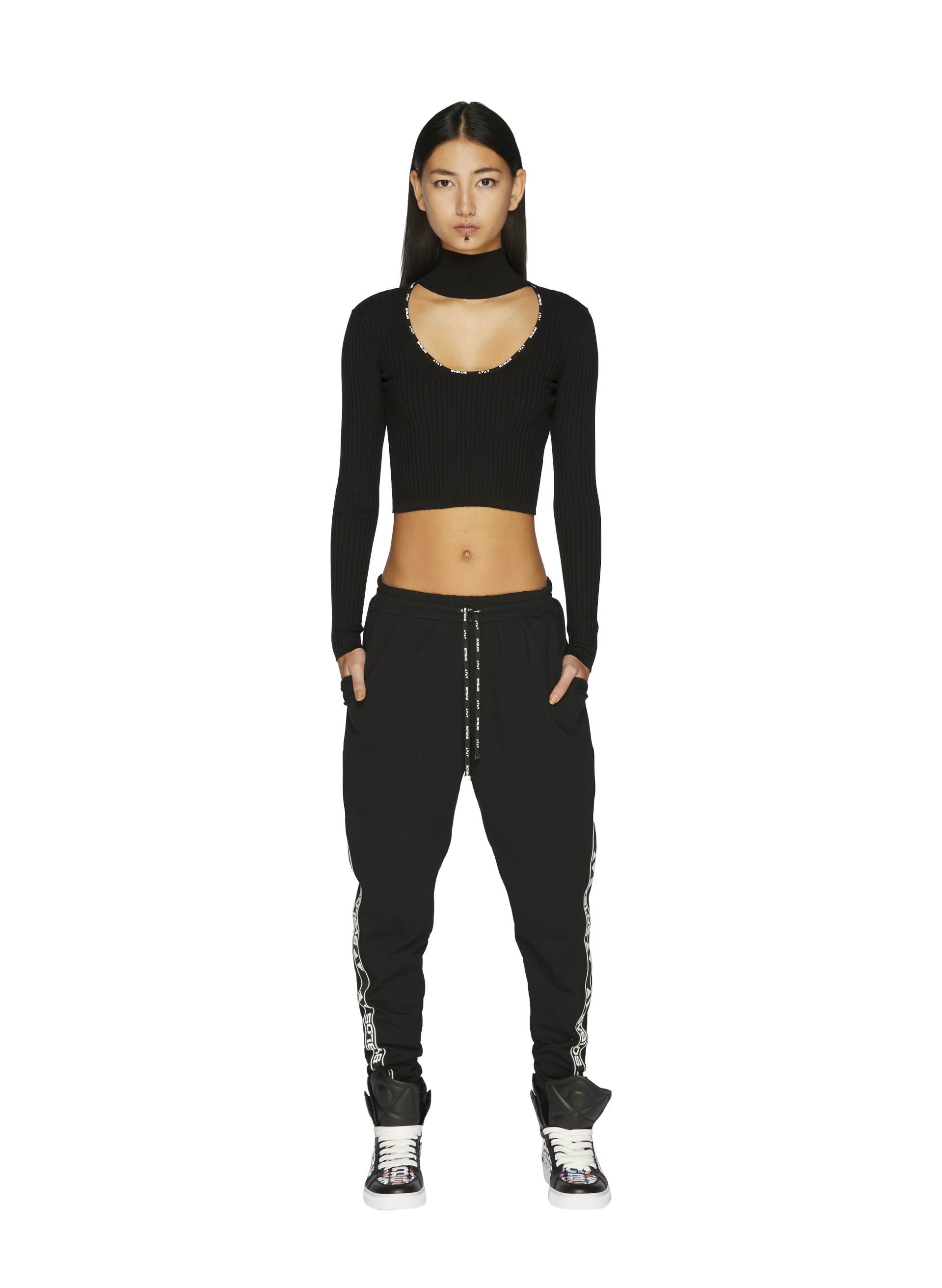 Model in a Knit Logo Crop Top with a unique neckline, paired with black joggers with side logo detailing and 3D Logo Iridescent Sneakers
