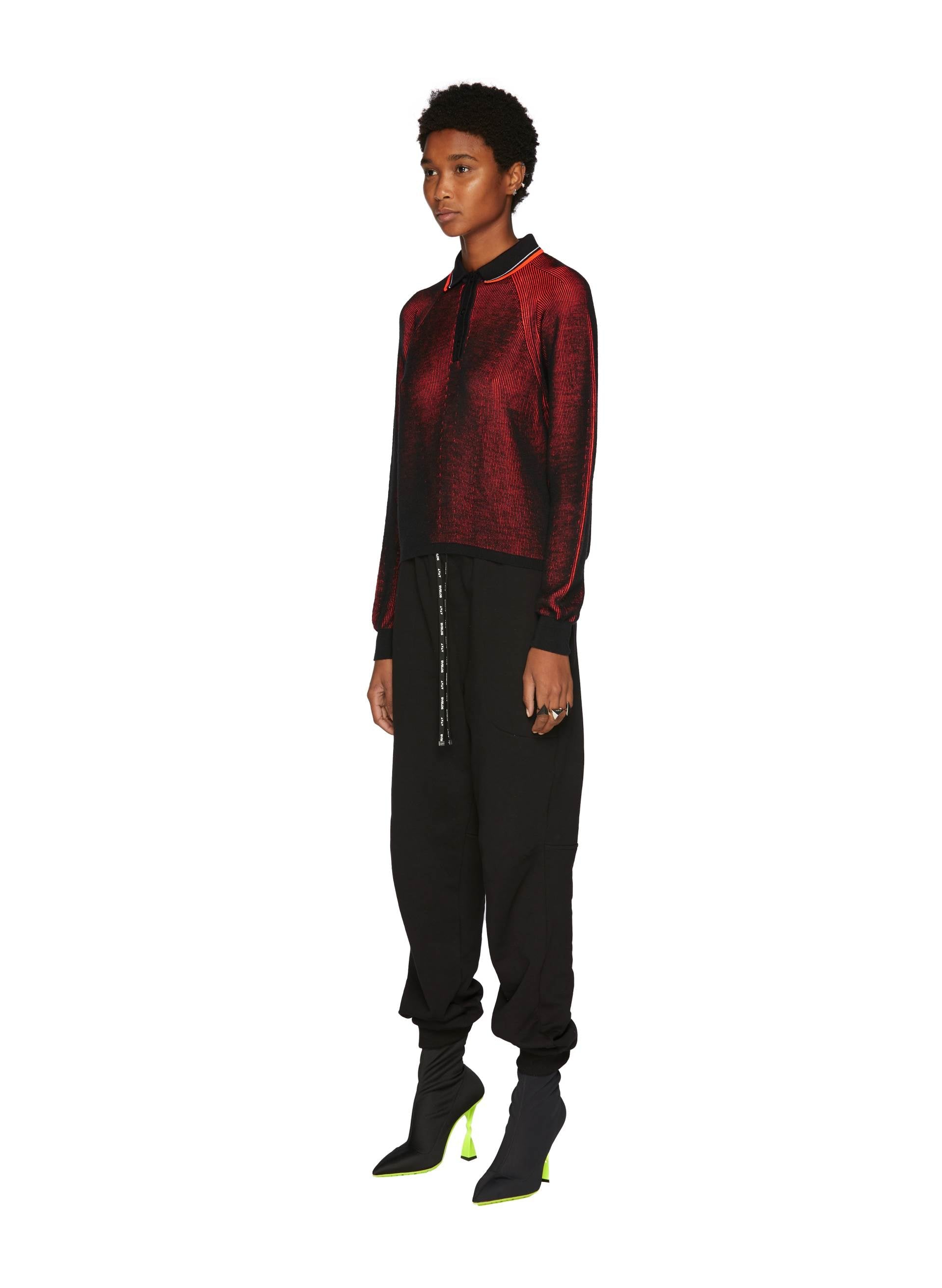 Red Knit Lines Maxi Polo paired with black joggers and striking green-heeled boots, showcasing contemporary Italian style.