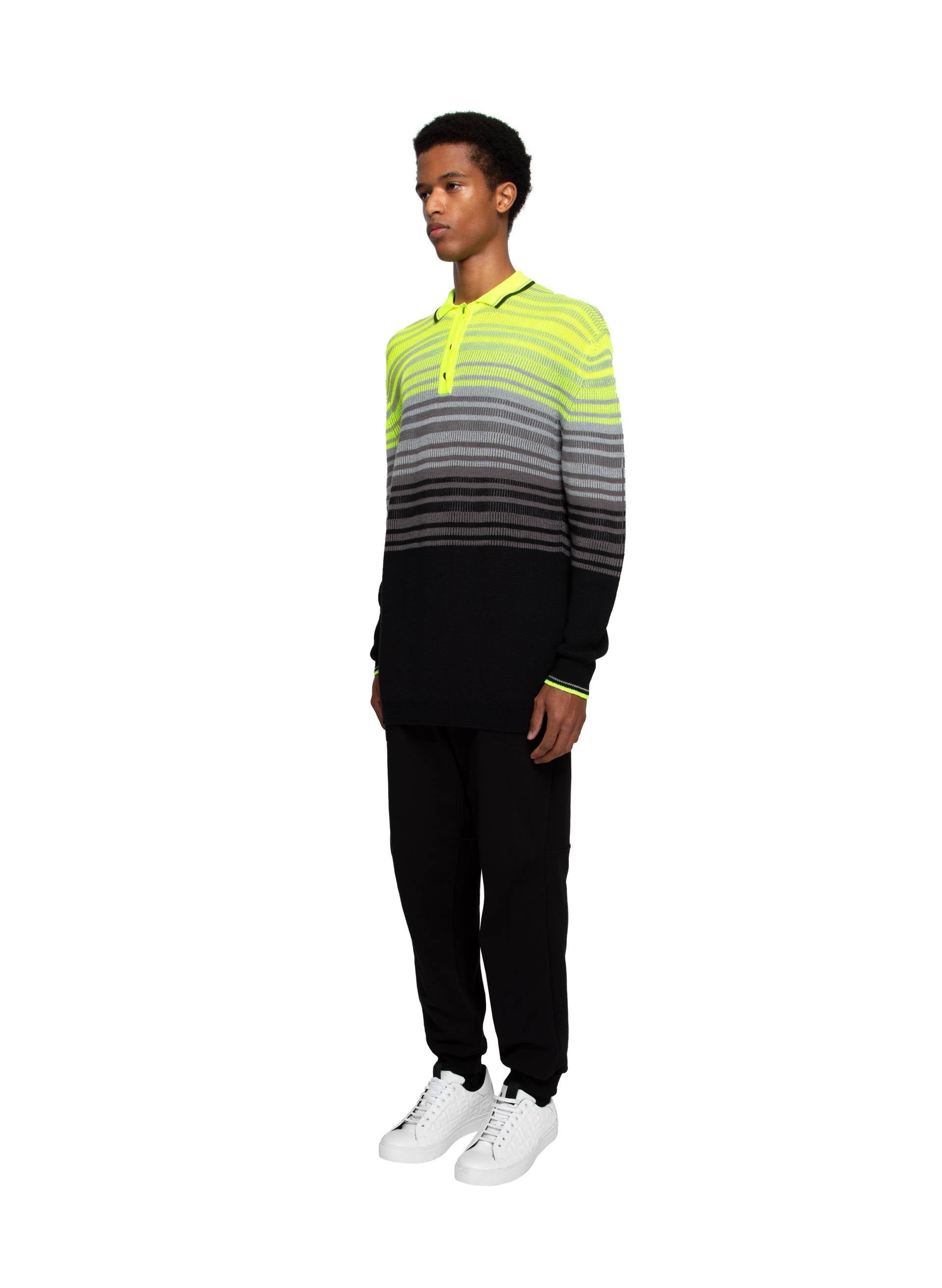 Striped knit fluo polo in vibrant yellow, gray, and black, paired with black joggers and white sneakers for a contemporary casual look.