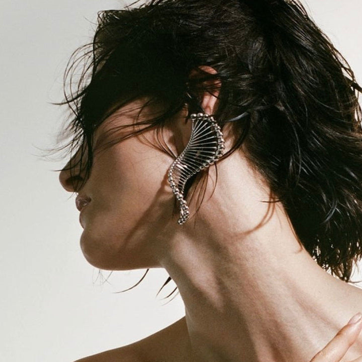 Woman with elegant earring and hand on shoulder, BAZAAR logo visible