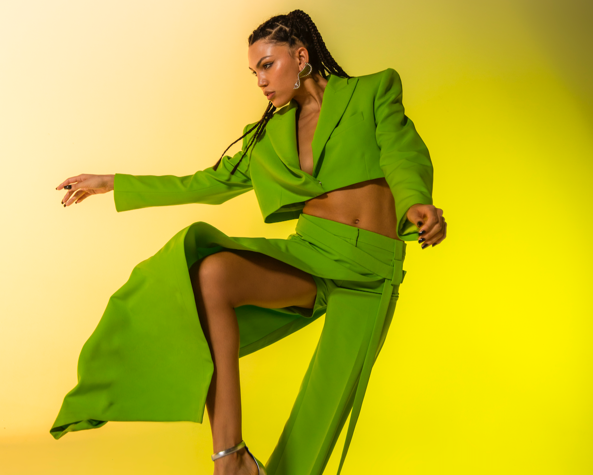 Person wearing a green outfit against a yellow background