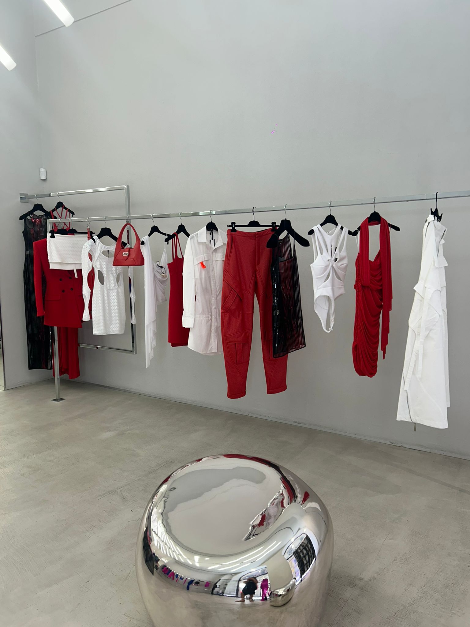 Display of red and white clothing in a minimalistic room with a reflective surface.