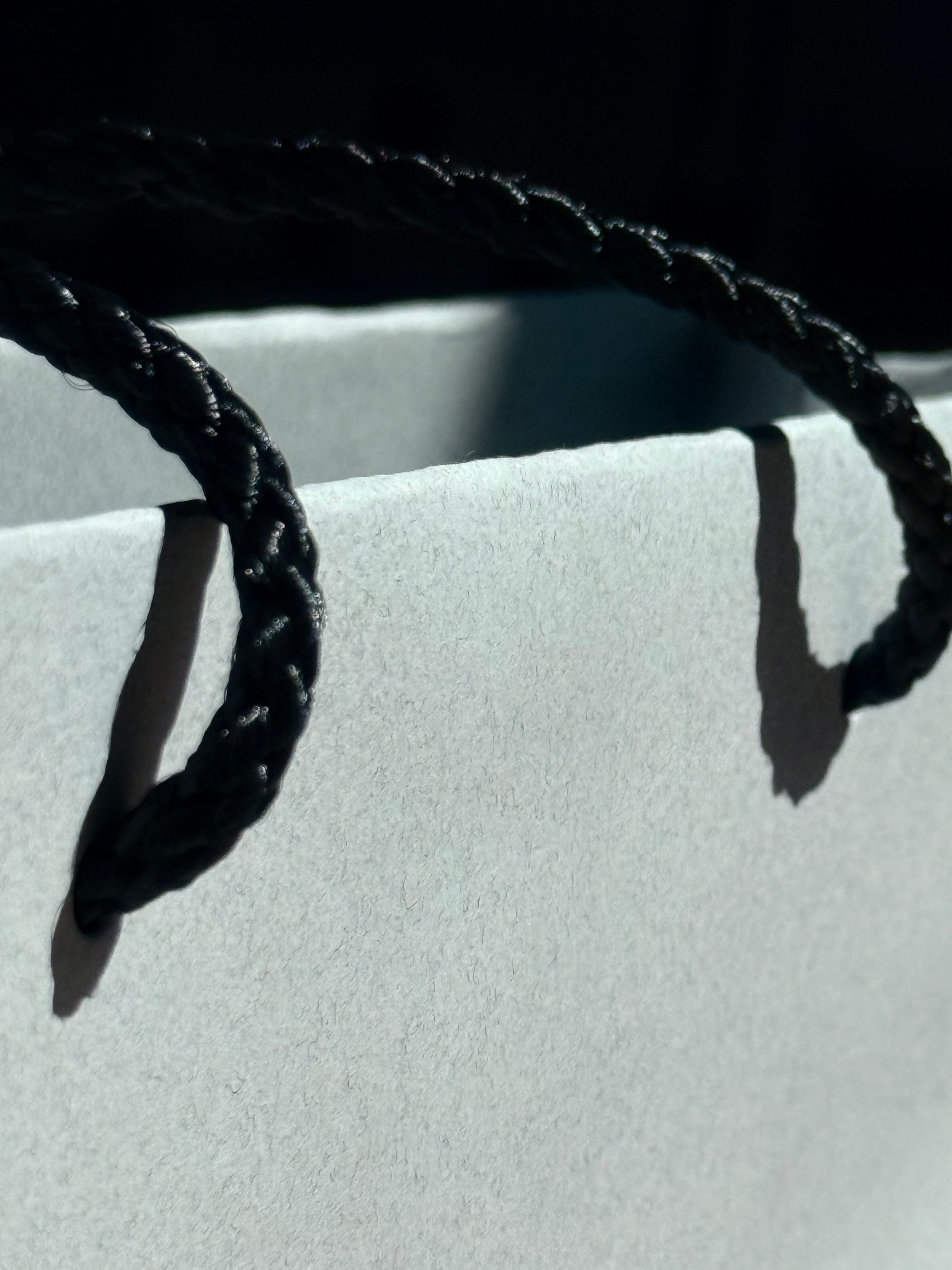 Close-up of a black rope tied around a white object with a dark background