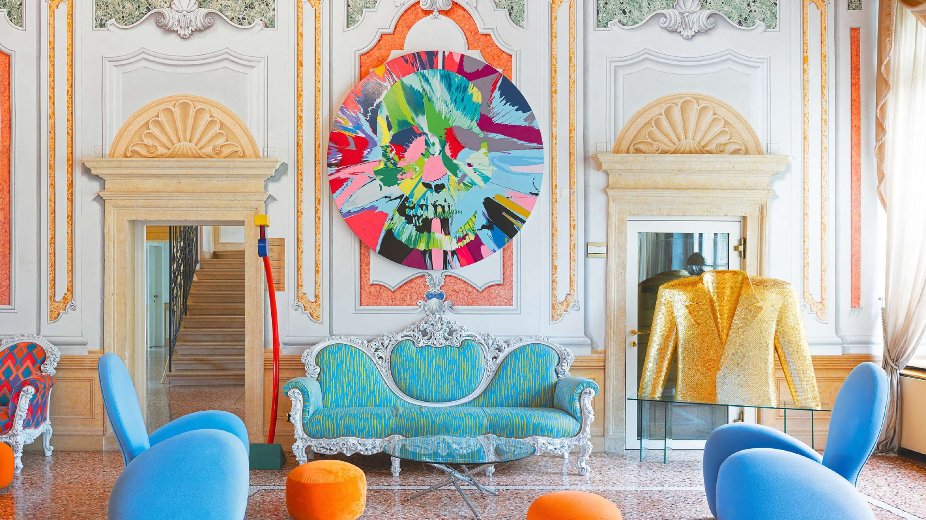 Decorative interior with a colorful abstract painting, blue sofa, and orange chairs.