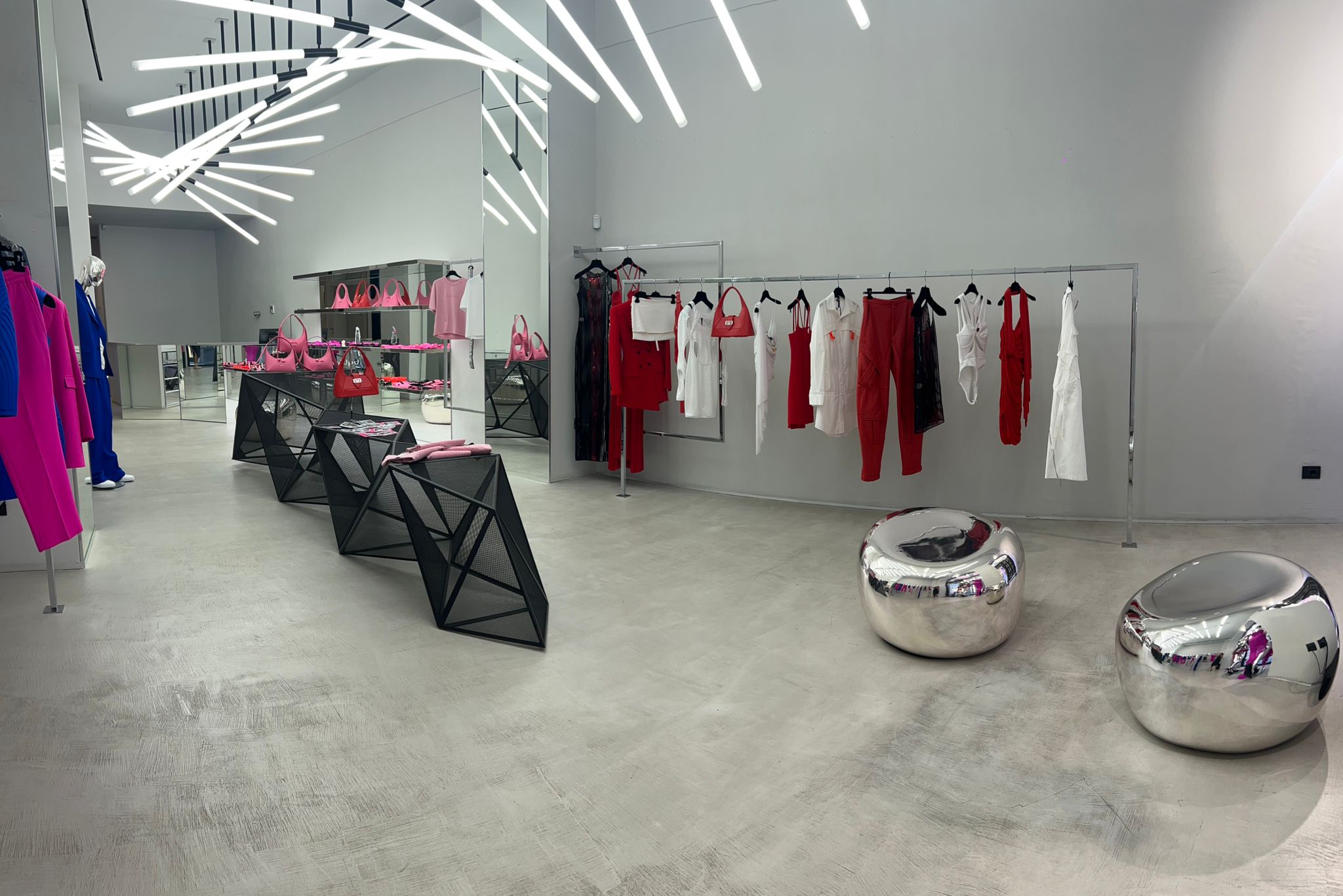 Modern clothing store interior with racks of clothes and reflective surfaces.