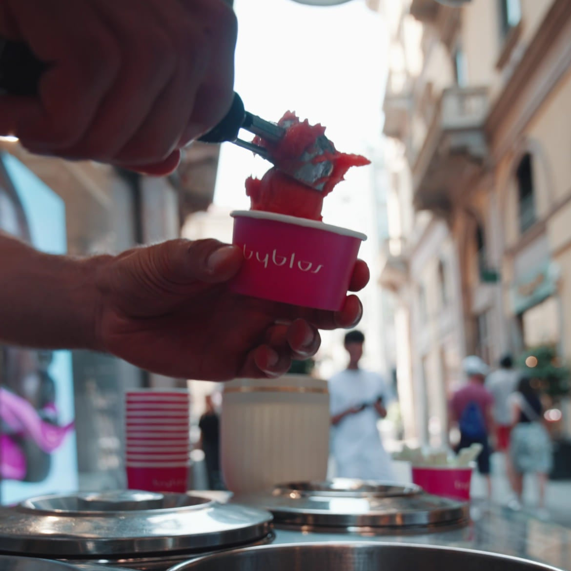 Person using a red ice cream scoop to serve ice cream from a container with 'Baskin-Robbins' branding.